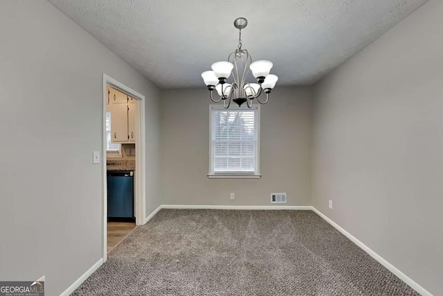 spare room featuring carpet floors, a textured ceiling, and a chandelier