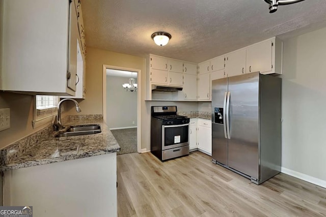 kitchen with light stone counters, white cabinetry, stainless steel appliances, and sink