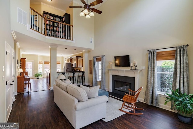 living room with ornate columns, a healthy amount of sunlight, dark hardwood / wood-style floors, and ornamental molding