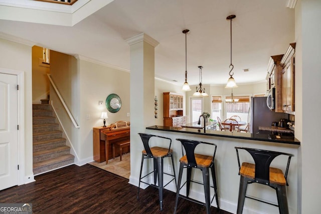 kitchen featuring crown molding, hanging light fixtures, dark hardwood / wood-style floors, kitchen peninsula, and stainless steel appliances