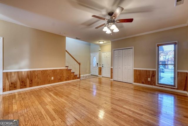 unfurnished room with crown molding, ceiling fan, light hardwood / wood-style floors, and wood walls