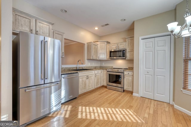 kitchen with pendant lighting, sink, light hardwood / wood-style flooring, appliances with stainless steel finishes, and light stone countertops