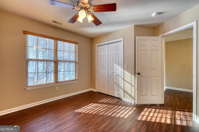 unfurnished bedroom featuring ceiling fan, dark hardwood / wood-style flooring, and a closet