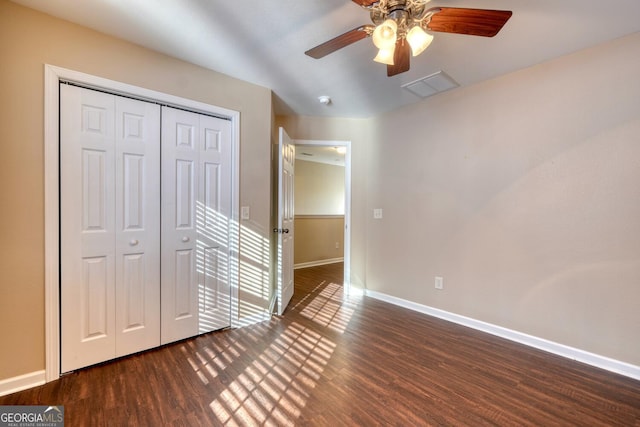 unfurnished bedroom featuring dark wood-type flooring, ceiling fan, and a closet