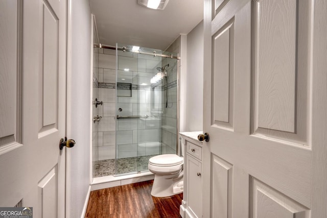 bathroom featuring hardwood / wood-style flooring, vanity, an enclosed shower, and toilet