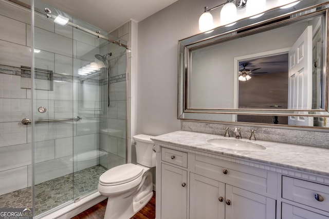 bathroom with toilet, an enclosed shower, vanity, ceiling fan, and hardwood / wood-style floors