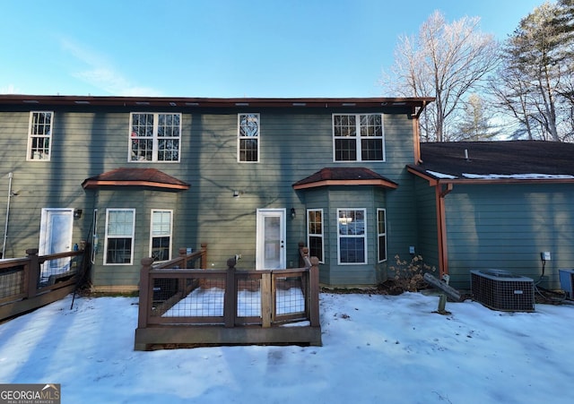 snow covered property with central air condition unit and a deck