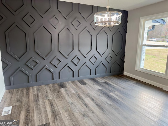 unfurnished dining area featuring wood-type flooring and an inviting chandelier