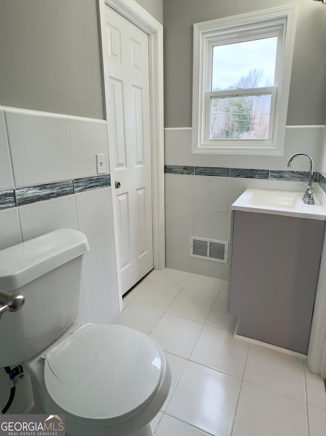 bathroom with vanity, toilet, tile patterned flooring, and tile walls