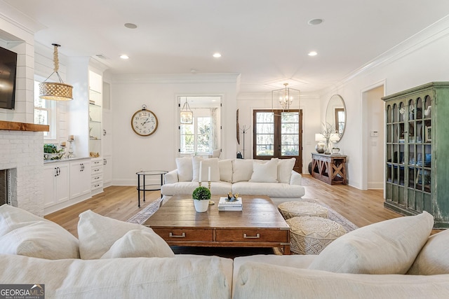 living room featuring french doors, crown molding, a fireplace, and light hardwood / wood-style flooring