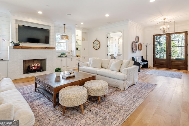 living room featuring crown molding, a healthy amount of sunlight, a fireplace, and light hardwood / wood-style flooring