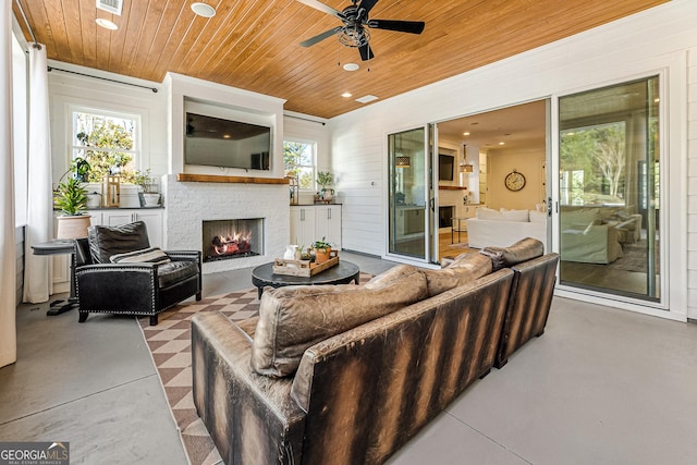 living room with ceiling fan, wood ceiling, a fireplace, and a healthy amount of sunlight