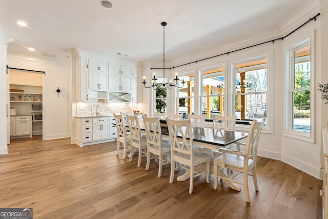 dining room with an inviting chandelier, ornamental molding, and light hardwood / wood-style flooring