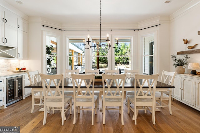 dining room with wine cooler, a notable chandelier, crown molding, and light hardwood / wood-style floors