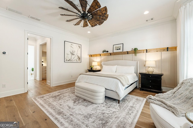 bedroom featuring hardwood / wood-style flooring, ornamental molding, and ceiling fan