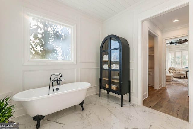 bathroom featuring ceiling fan, ornamental molding, and a washtub