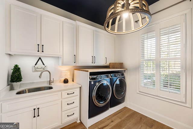 laundry room featuring sink, wood-type flooring, cabinets, and washer and dryer