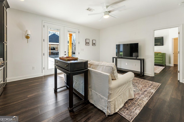 living room featuring dark wood-type flooring and ceiling fan