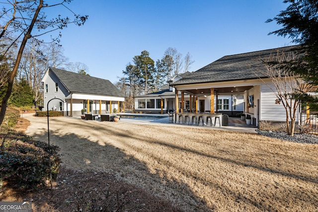 rear view of property featuring a patio area, an outdoor bar, and a lawn