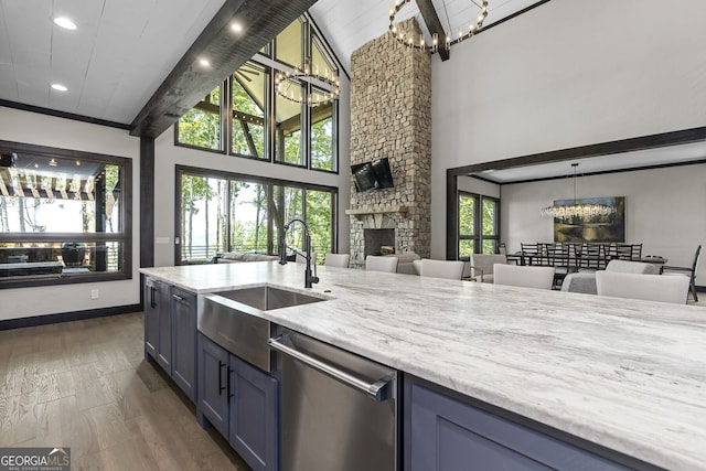 kitchen with a stone fireplace, decorative light fixtures, dishwasher, sink, and a chandelier