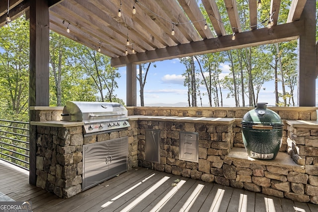 wooden deck featuring exterior kitchen, area for grilling, and a pergola