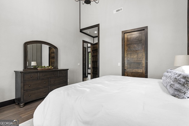 bedroom featuring dark hardwood / wood-style flooring and a high ceiling