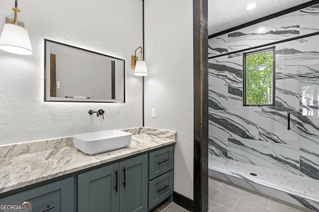 bathroom with a tile shower and vanity