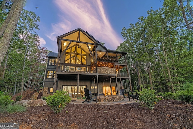 back house at dusk featuring a fire pit and a patio area