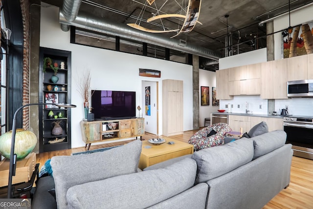 living area featuring light wood-style floors and a high ceiling