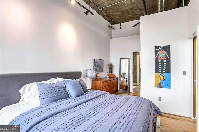 bedroom featuring a high ceiling and wood finished floors