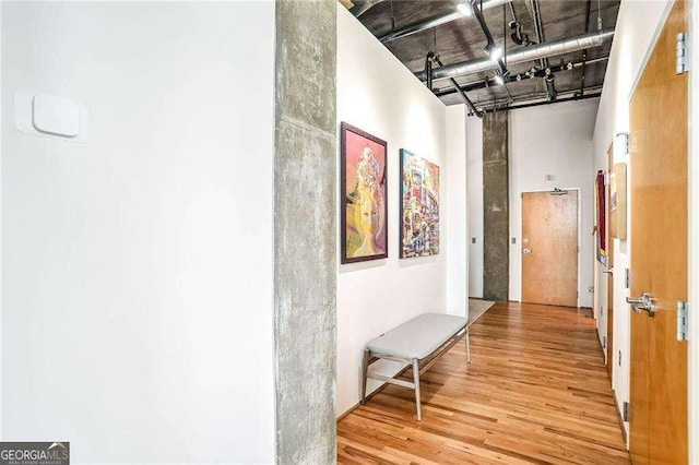 hallway featuring a towering ceiling and wood finished floors