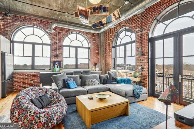 living room with wood finished floors, a high ceiling, and brick wall