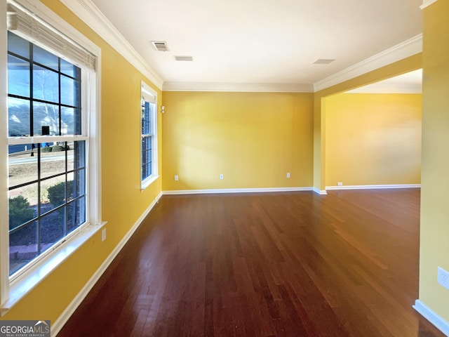 spare room with crown molding, a healthy amount of sunlight, and dark hardwood / wood-style floors