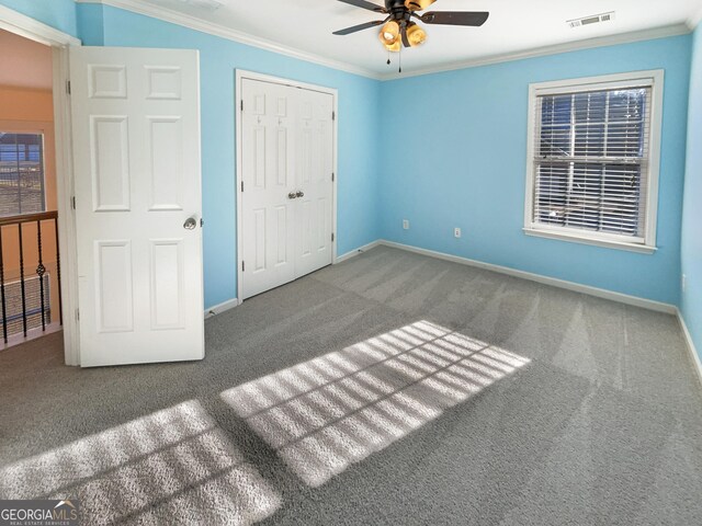 unfurnished bedroom featuring ceiling fan, ornamental molding, carpet floors, and a closet