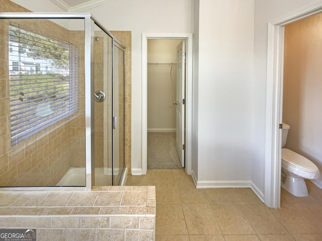 bathroom with a shower with door, tile patterned floors, and toilet