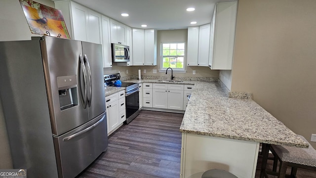 214 Harris St, Chatsworth, GA 30705 - kitchen with white cabinetry, stainless steel appliances, dark wood-type flooring, a sink, and a peninsula