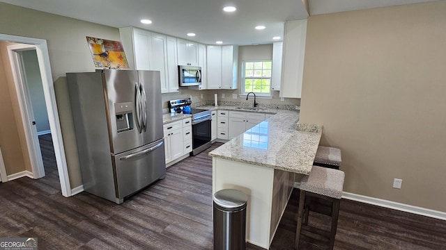 214 Harris St, Chatsworth, GA 30705 - kitchen featuring a kitchen bar, stainless steel appliances, dark wood finished floors, a sink, and a peninsula