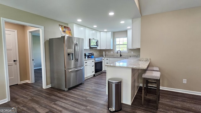 214 Harris St, Chatsworth, GA 30705 - kitchen featuring a breakfast bar, white cabinetry, a peninsula, and appliances with stainless steel finishes