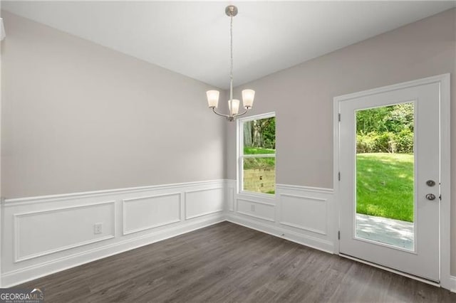 unfurnished dining area featuring dark hardwood / wood-style flooring and a notable chandelier