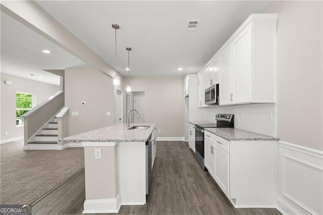 kitchen featuring sink, a kitchen island with sink, stainless steel appliances, light stone counters, and decorative light fixtures