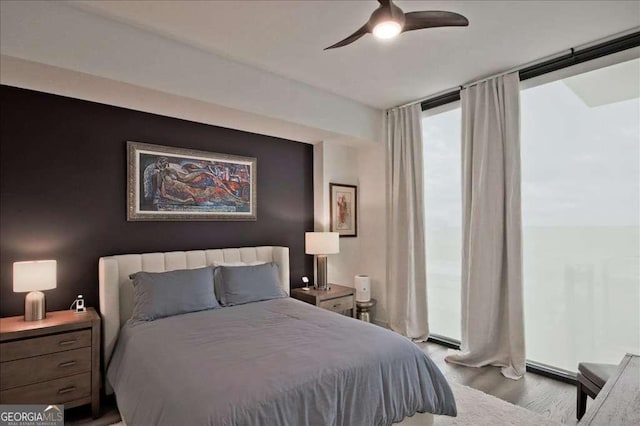 bedroom with expansive windows, ceiling fan, and light hardwood / wood-style floors