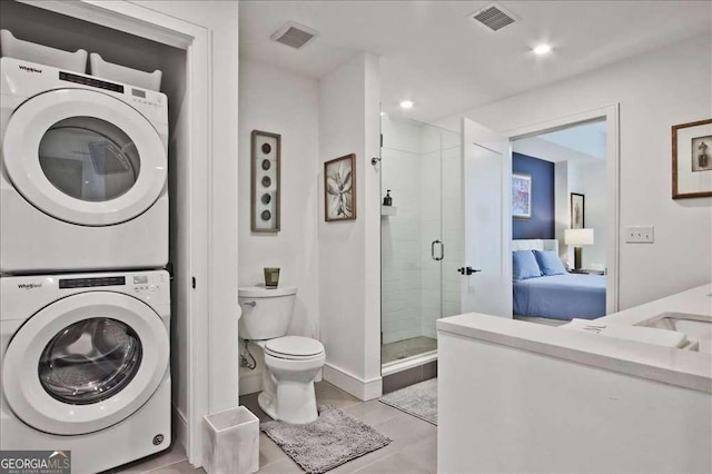 bathroom featuring stacked washer and clothes dryer, toilet, and a shower with door