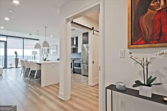 kitchen featuring appliances with stainless steel finishes, sink, a breakfast bar area, hanging light fixtures, and a barn door