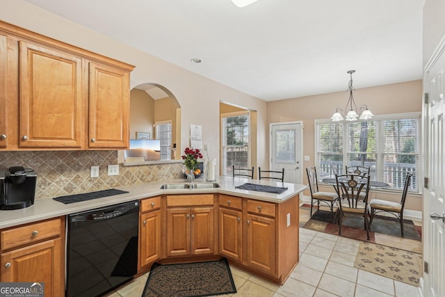 kitchen with a peninsula, a sink, light countertops, hanging light fixtures, and dishwasher