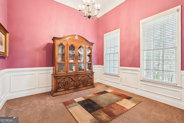 interior space with an inviting chandelier, crown molding, carpet flooring, and wainscoting