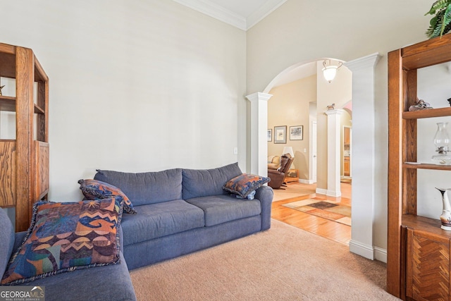 carpeted living area with ornamental molding, arched walkways, ornate columns, and wood finished floors