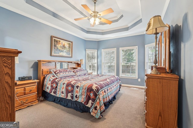 bedroom featuring a tray ceiling, ornamental molding, light carpet, ceiling fan, and baseboards