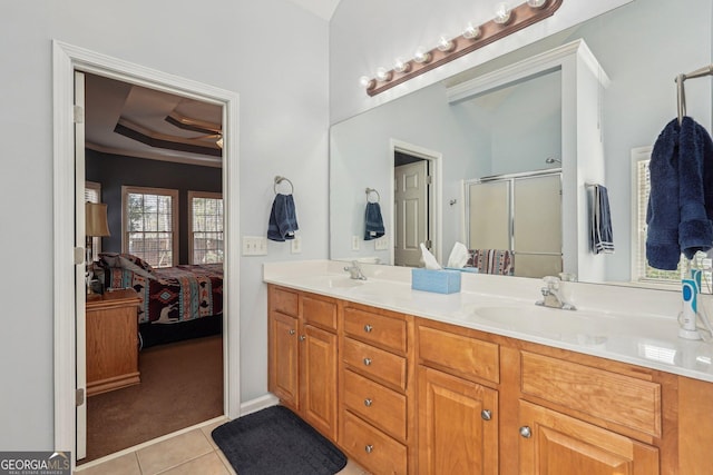 full bath with a tray ceiling, ensuite bathroom, a sink, a shower stall, and tile patterned flooring