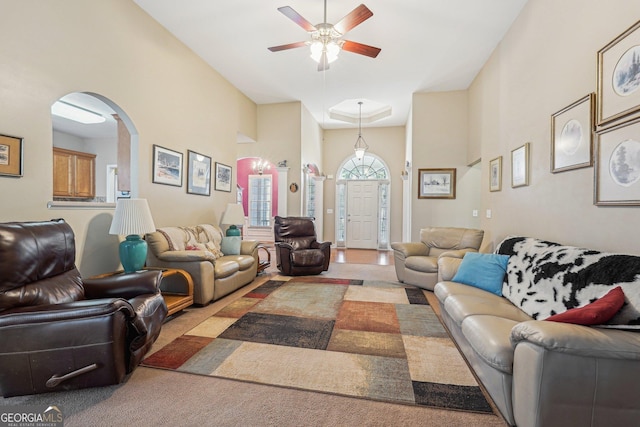 living area with arched walkways, a ceiling fan, and light colored carpet