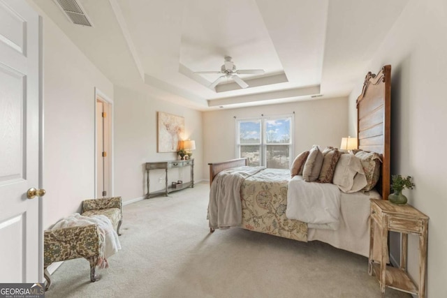 carpeted bedroom featuring ceiling fan and a tray ceiling